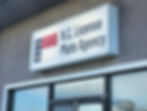 A North Carolina flag and the words, "N.C. License Plate Agency" appear on a white sign