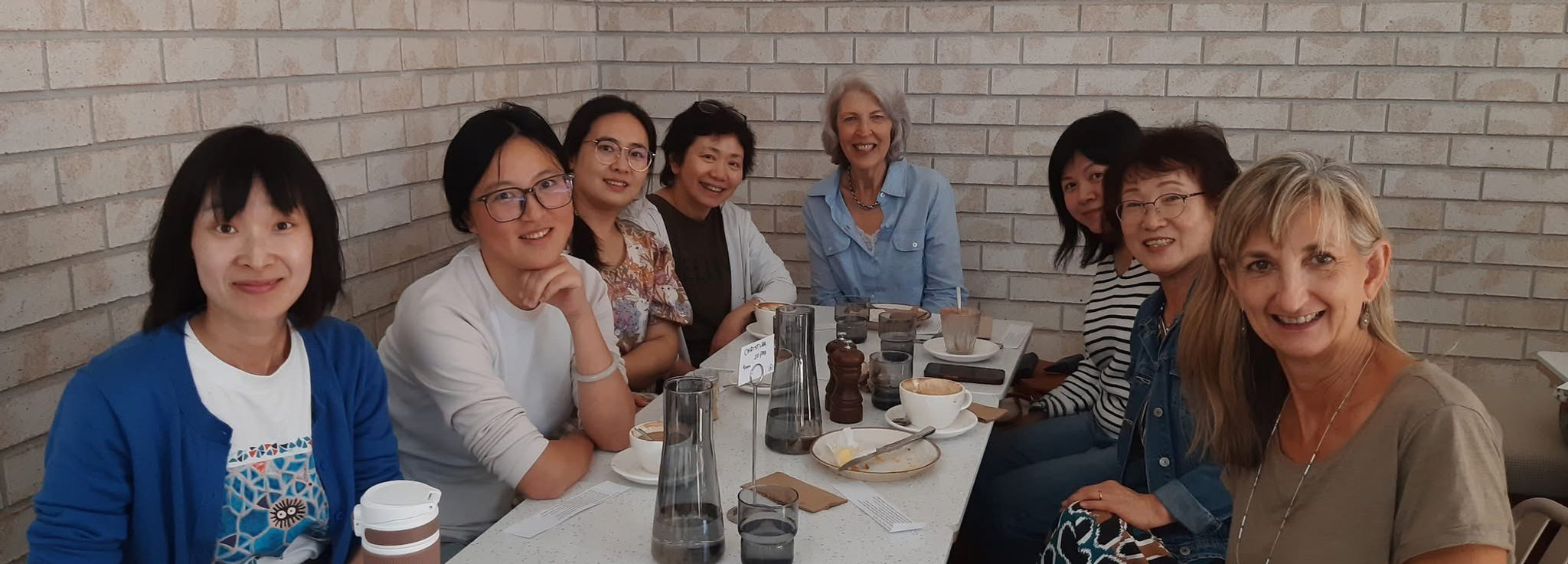 Adult English learners practising everyday conversational English at a Talk Time Tutoring coffee group in North Shore, Auckland.