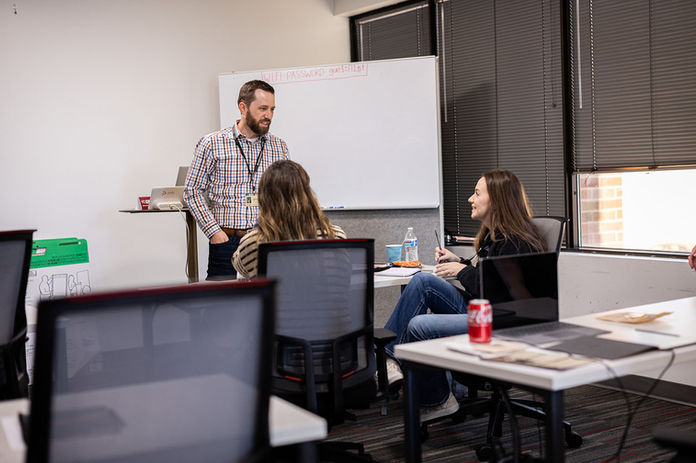 A presenter in a conference room talks to a participant 
