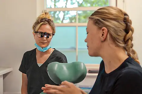 White Dental clinician speaking with a patient during a dental appointment.