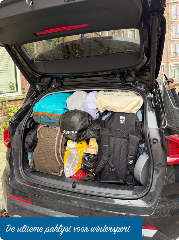 Afbeelding van een overvolle ingepakte achterbak van een auto, gevuld met skihelmen, kledinglagen, handschoenen en skibrillen, illustrerend hoe je slim kunt inpakken voor een skivakantie
