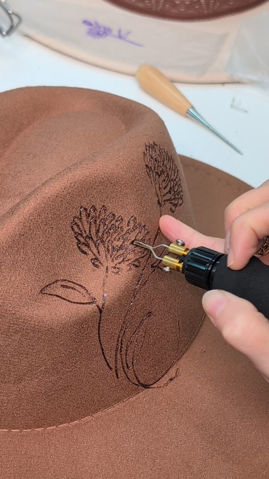 Hand-burning delicate flowers onto a bespoke Prairie Jane hat