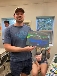 July 15, 2023 Parks Day Paint Party participant proudly shows off his night sky northern lights painting