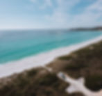 van parked in front of turquoise beach at bay of fires in tasmania