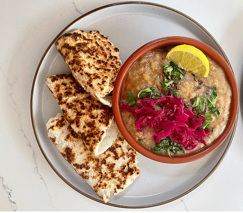 Coconut flatbreads paired with vibrant lentil soup, garnished with fresh herbs, pickled cabbage, and tangy lemon