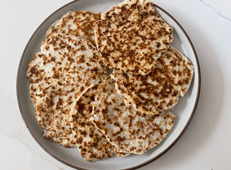 Eye-level view of golden-brown coconut flatbreads on a wooden board