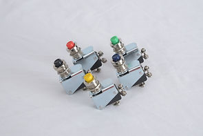 The image shows five industrial limit switches clustered together. Each switch has a distinct colored button on top: red, green, yellow, blue, and black. These switches are typically used in machinery to detect the presence or absence of an object or to monitor the position of moving parts. The different colors likely indicate different functions or statuses for each switch.