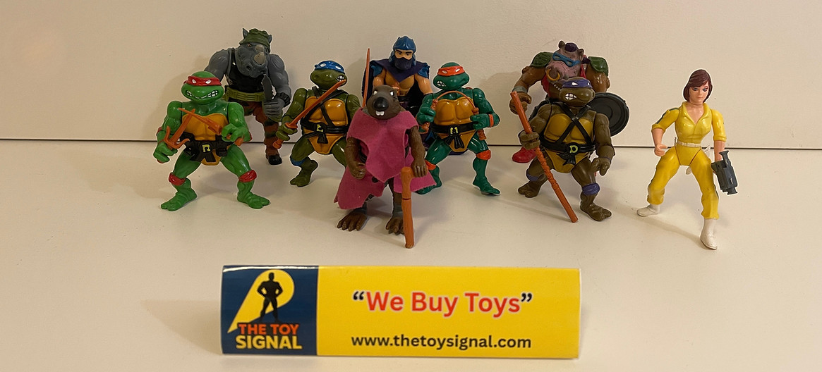 Vintage Teenage Mutant Ninja Turtles action figures including Raphael, Leonardo, Donatello, Michelangelo, Splinter, April O’Neil, Shredder, Bebop, and Rocksteady from the 1988 Playmates line, displayed in front of a “We Buy Toys” sign from The Toy Signal.