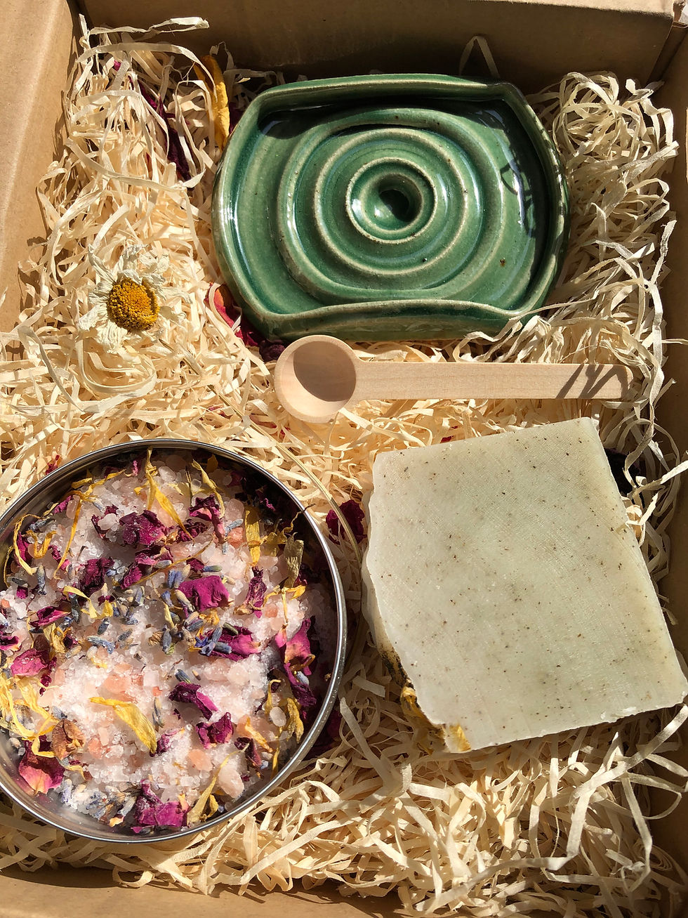 Thumbnail: A green ceramic soap dish along with a mint and nettle soap , a wooden spoon and bath salts infused with botanicals.
