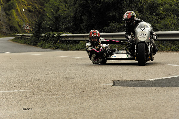 Un side-car ancien engagé dans un virage de la Montée Classic du Viaduc de Millau, avec le passager très bas pour accompagner l’équilibre de la machine.