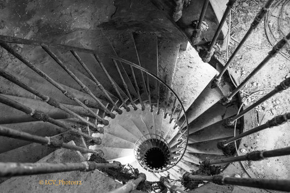Escalier en colimaçon d’un ancien couvent abandonné photographié en noir et blanc.