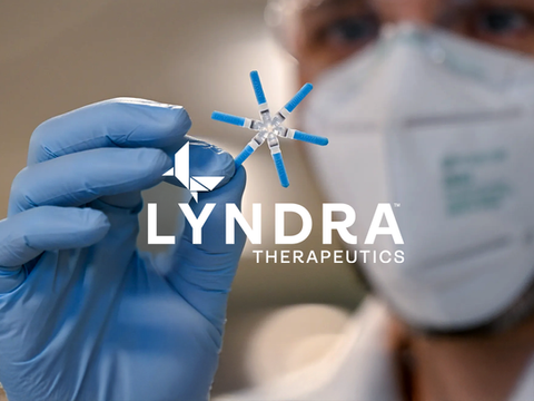 Logo over scientist holding the Lyndra Lynx