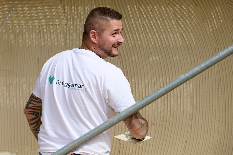 Ein netter motivierter Malervorarbeiter der ein Fassade bearbeitet