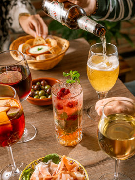 Tisch mit spanischen Drinks: Sangria, Bier, Wein und ein fruchtiger Cocktail mit Oliven und Brot