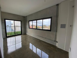 Quarto residencial em estilo industrial com piso de concreto polito, placas de concreto pré-moldada na parede, porta janela com grade e janela grande.