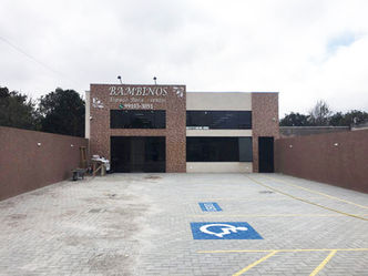 Fachada de obra comercial térreo com grandes janelas e revestimento de pastilhas em tom de bege e marrom.