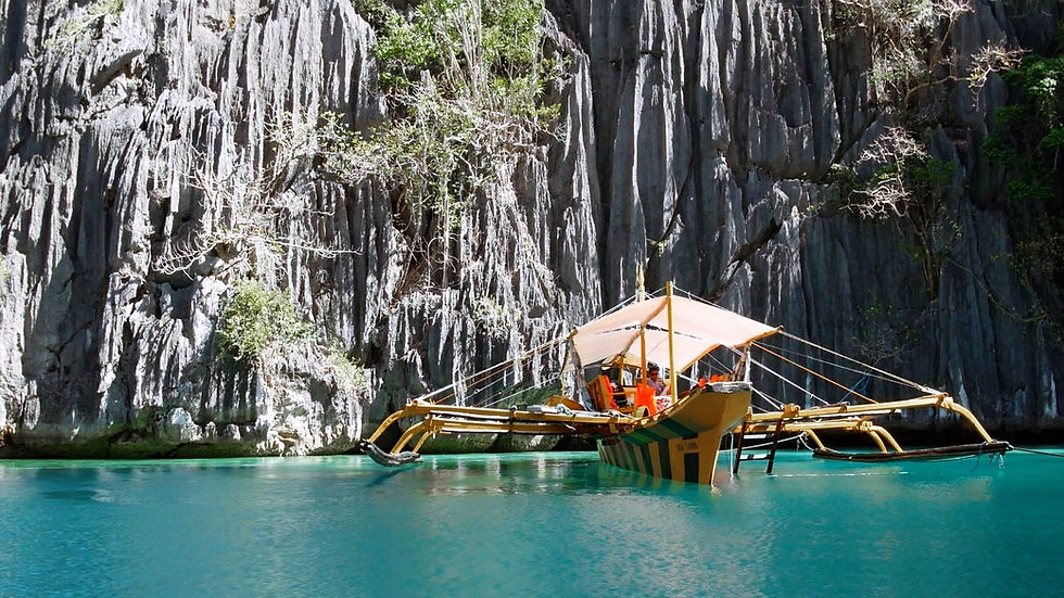 Une banca, bateau traditionnel philippin, navigue dans les eaux cristallines de Twin Lagoon à Coron, entourée de falaises karstiques spectaculaires