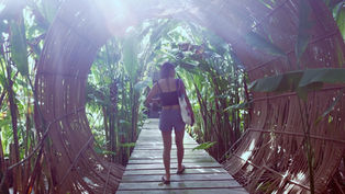 Jeune femme traversant le pont de bambou et le tunnel végétal du Nacpan Beach Resort à El Nido.