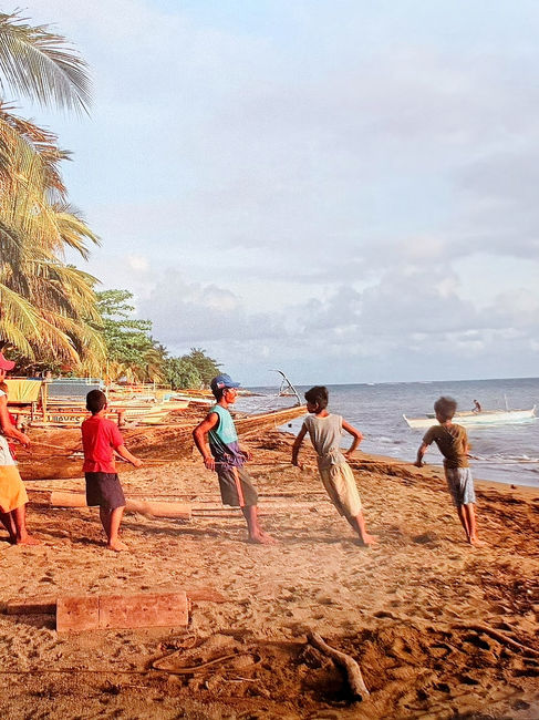 Scène de vie locale montrant des pêcheurs philippins unissant leurs forces pour remonter une banca sur le sable de la plage de Paniman à Caramoan dans les années 2000, un rituel quotidien immuable
