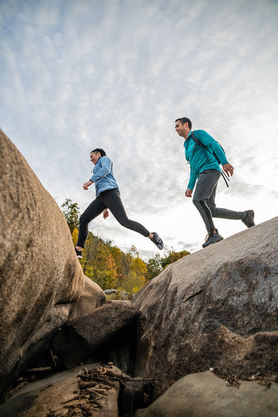 A man and woman jumping over a crevice while hiking in Richmond, Virginia