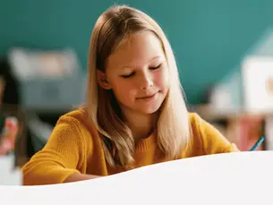 Zufrieden schauende Kind beim lernen am Schreibtisch