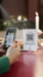 Invitado escaneando un código QR colocado en una mesa de boda para compartir fotos en tiempo real con Selfipix.