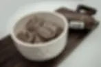 photo of a bowl of Four Roots Green Beef Tripe product with a chub beside it.