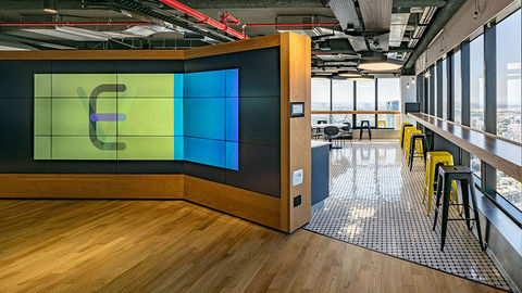 Commercial lobby video wall showing branded content and a compact equipment rack with labeled cabling.