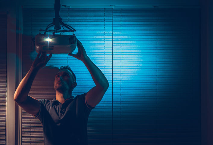 Technician calibrating projector for optimal picture quality