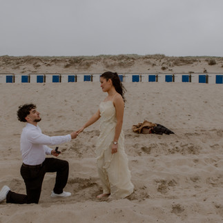 man vraagt vrouw ten huwelijk tijdens fotoshoot op het strand