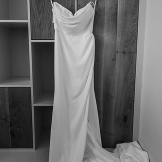 Trouwjurk hangend bij raam met daglicht tijdens getting ready op bruiloft