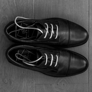 Schoenen bruidegom klaar gelegd voor detailfoto’s tijdens de ochtend van de bruiloft