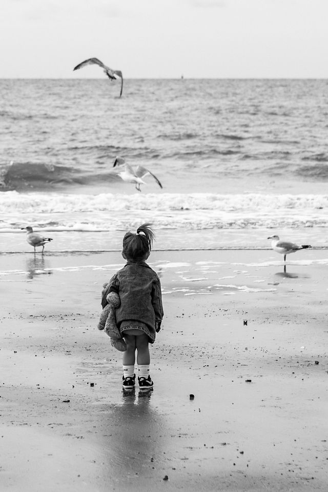 meisje op het strand lopend naar de zee met meeuwen op de achtergrond