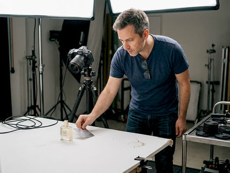 Un photographe s’installe en studio pour réaliser des photos packshot, ajustant éclairages et accessoires afin de mettre en valeur les produits.