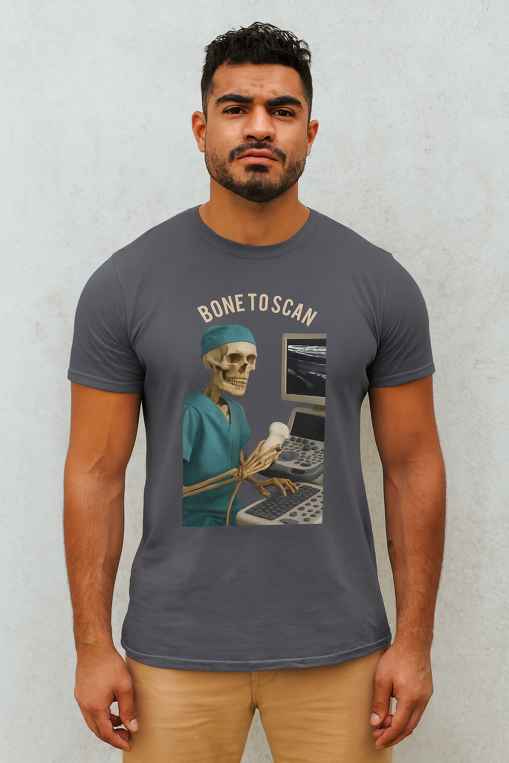 Skeleton wearing teal scrub cap and top holding an ultrasound probe in front of machine bold text Bone to Scan on t-shirt