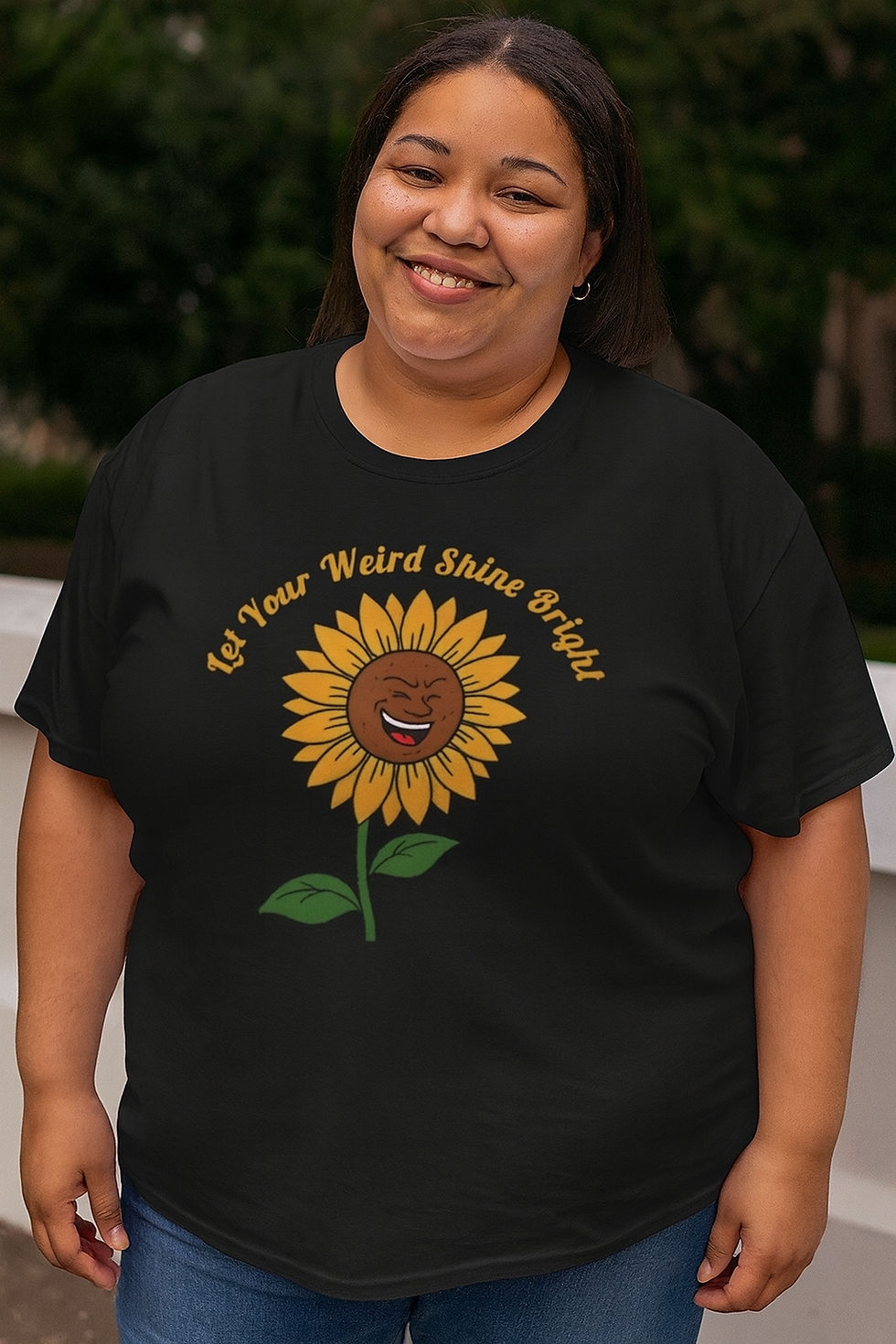 Black tee with yellow text Let your weird shine through arched over a smiling cartoon sunflower