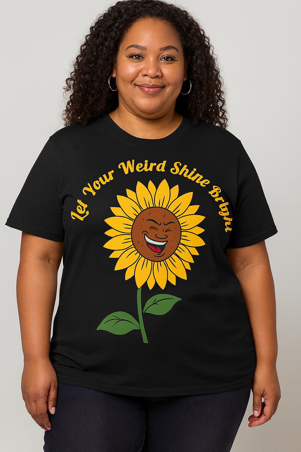 Black tee with yellow text Let your weird shine through arched over a smiling cartoon sunflower