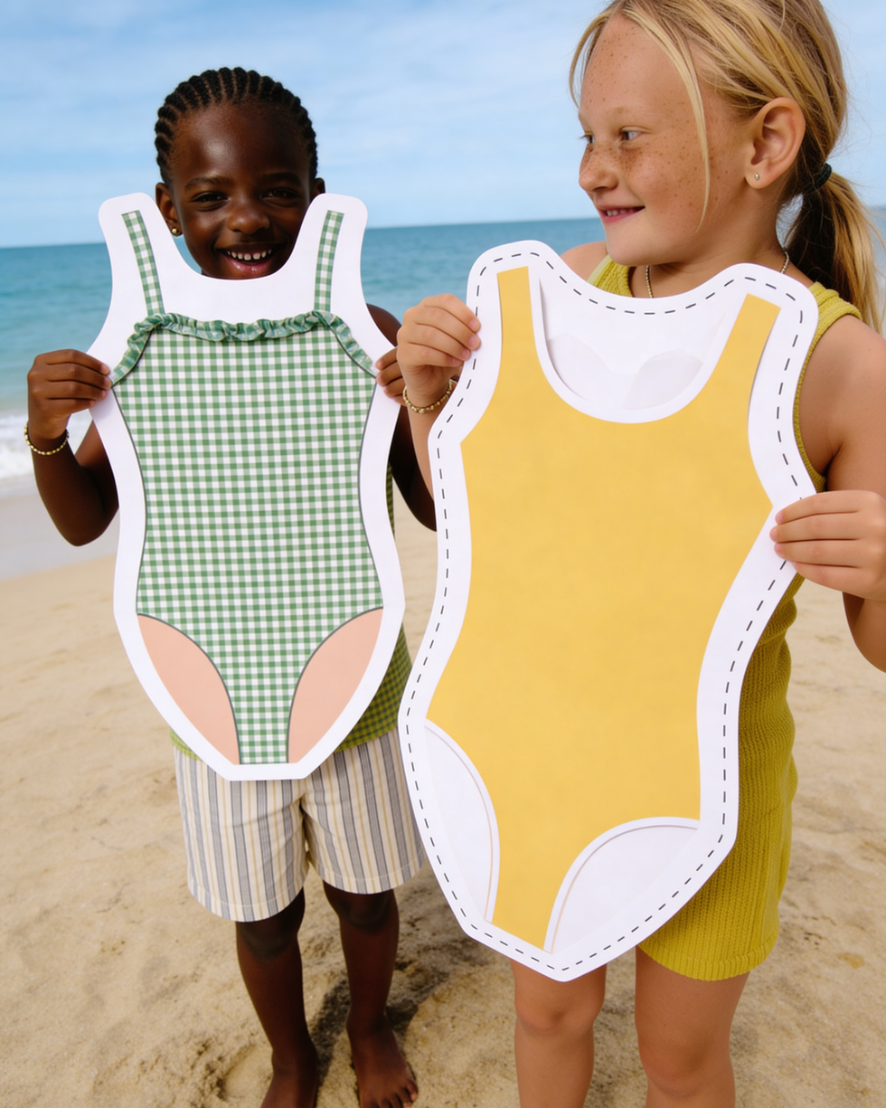 Two children holding swimsuit cutouts on a beach.