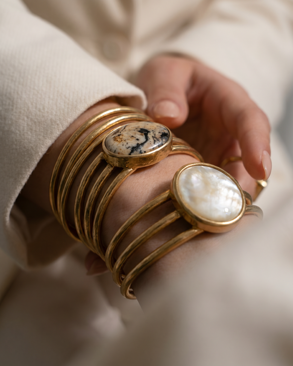 Person wearing multiple gold bangles with decorative stones.