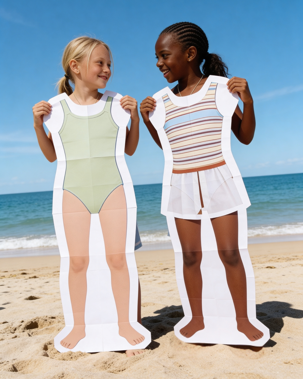 Two children holding cutout figures on a beach.