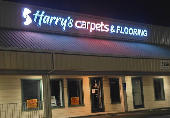 The prominent exterior storefront of Harry's Carpets in Vacaville, California, featuring a large illuminated sign visible from the I-80 freeway, showcasing our landmark location as a premier flooring destination in Solano County.