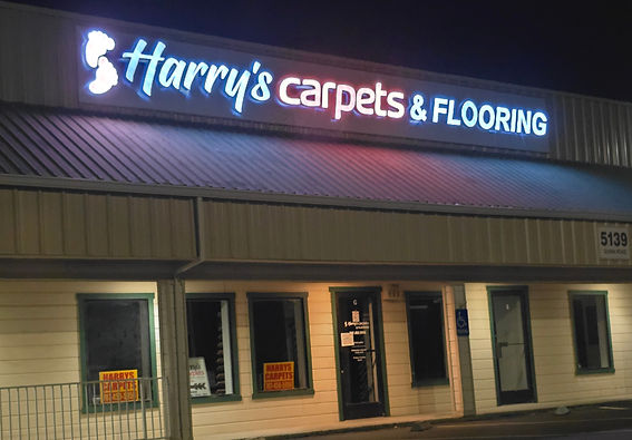 The prominent exterior storefront of Harry's Carpets in Vacaville, California, featuring a large illuminated sign visible from the I-80 freeway, showcasing our landmark location as a premier flooring destination in Solano County.