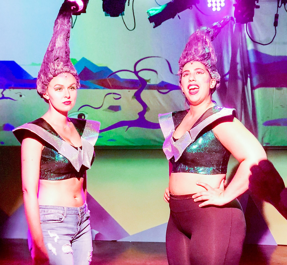 Two Wild Women from the mysterious Planet Won- go stand and joke as a light cue is built around them.