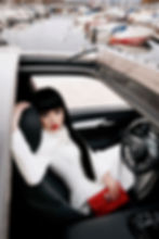 Jessica Minh Anh in white AI Generated couture look by UAE fashion house MAGNO MONTERO in a red VinFast VF8 for Luxury in Motion campaign in Geneva