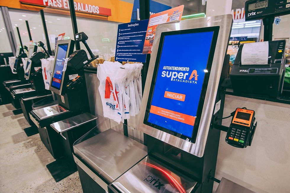 Caixas de autoatendimento do Super A, com telas azuis, cartões e sacolas, em corredor de supermercado iluminado.