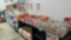 Corredor de pet shop com sacos de ração empilhados e placas de preço na parede; ambiente organizado e comercial.