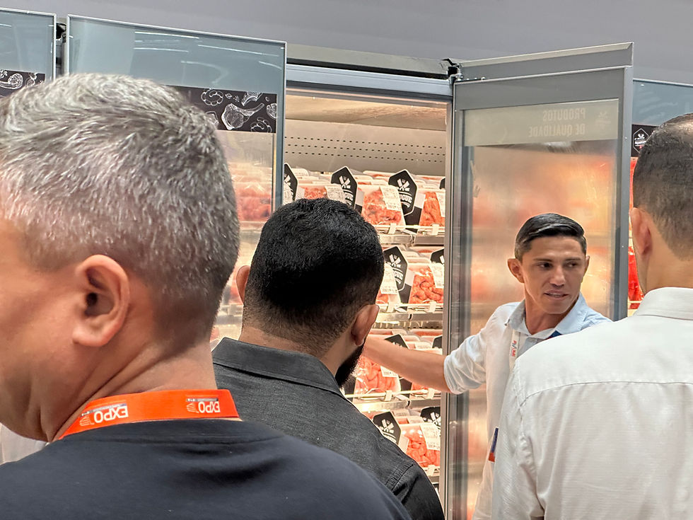 Vários homens observam um refrigerador de carnes; um funcionário aponta produtos em um corredor de supermercado.