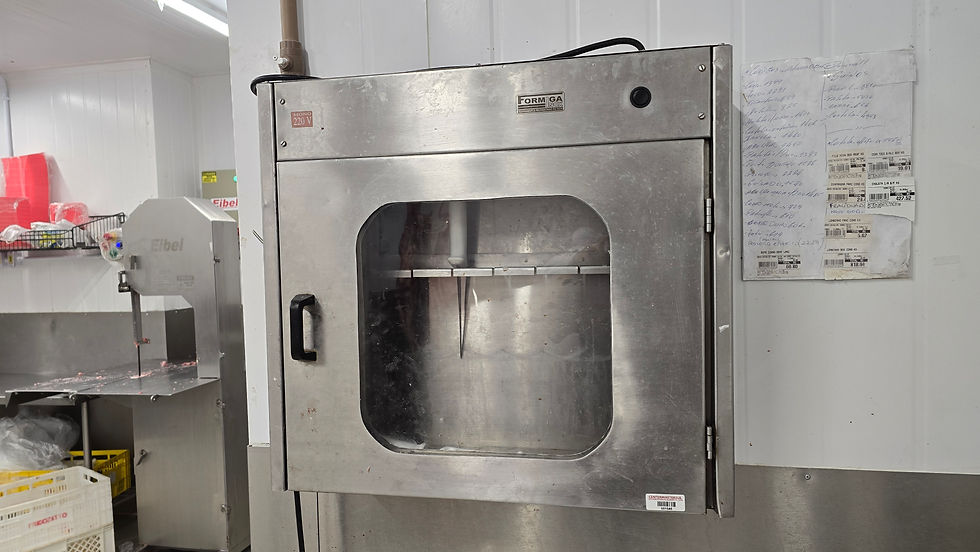 Forno de aço inoxidável em cozinha industrial com notações escritas em papel colado na parede ao lado. Máquina Eibel ao fundo.