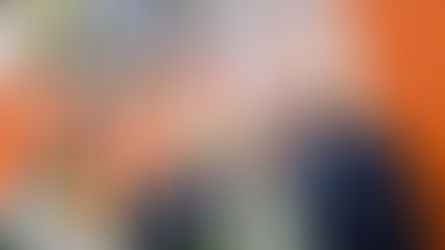 Três homens sorridentes em estande laranja de feira de tecnologia, com crachás e painéis da Prix e Toshiba ao fundo. Oscar da Automação Telecon.