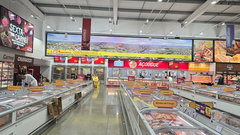 Corredor de açougue em supermercado, com vitrines de carnes e placas AÇOUGUE, ASSADOS e CONGELADOS; funcionários atendem.